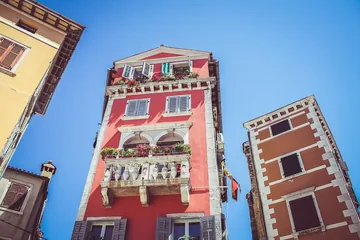Photo looking up at red and yellow townhouses under a blue sky