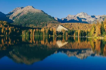 Photo of a mountain lake with autumn trees reflected in the water